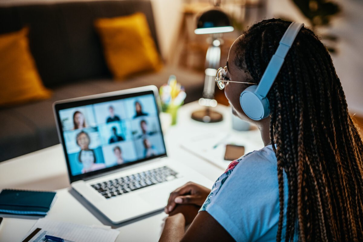 An African American female is having an online meeting with a group of unrecognizable international students.